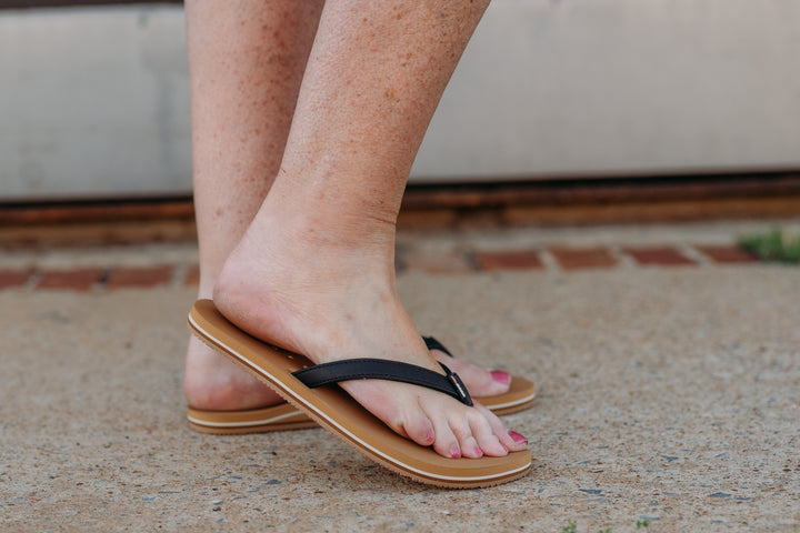 Close-up of a person's foot wearing a black and tan Reef Solana sandal.