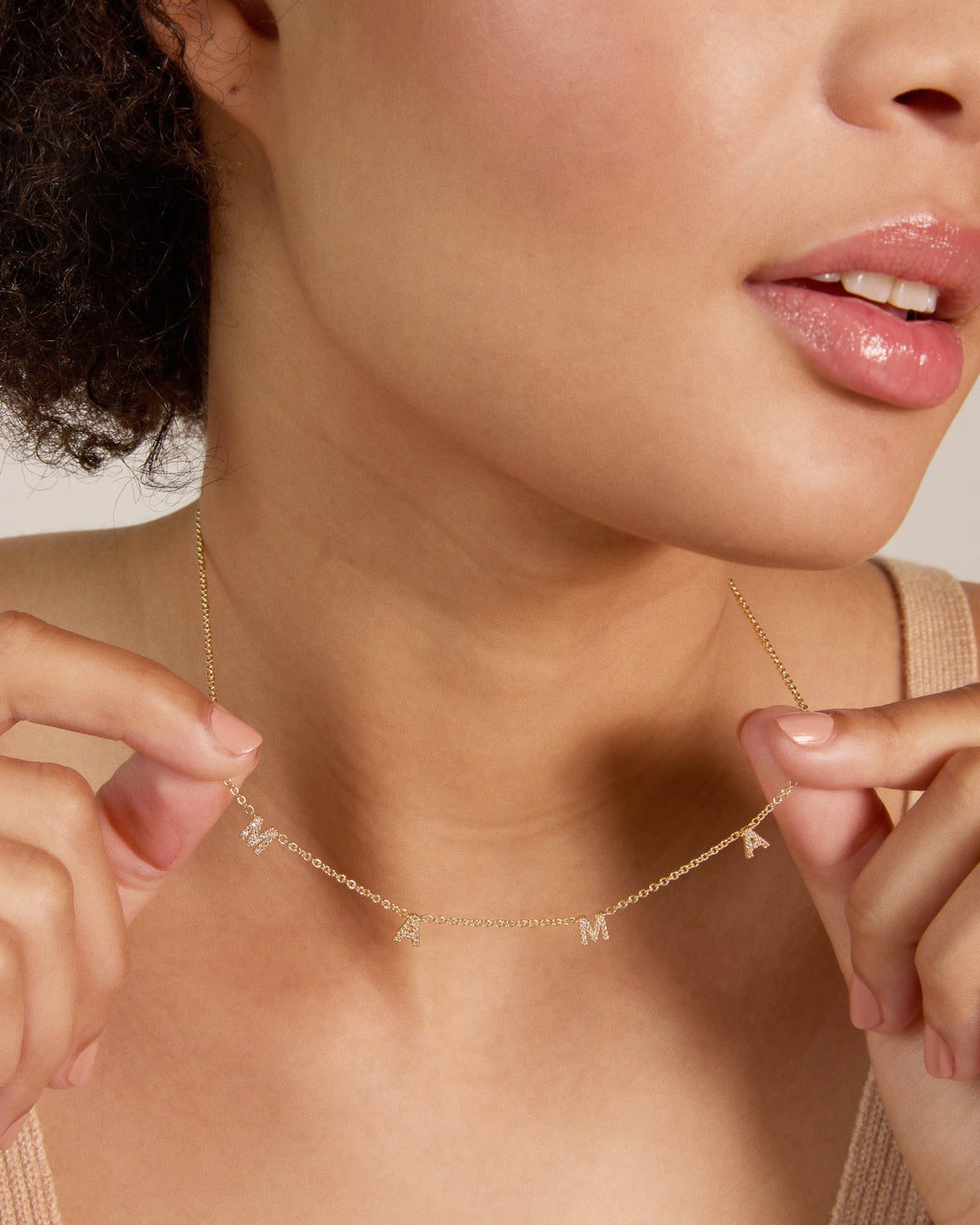 Model wearing delicate gold chain necklace with letter charms spelling MAMA