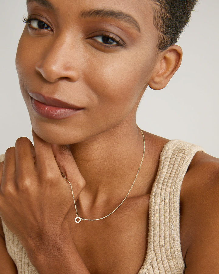 Woman wearing delicate silver chain necklace with small circular pendant