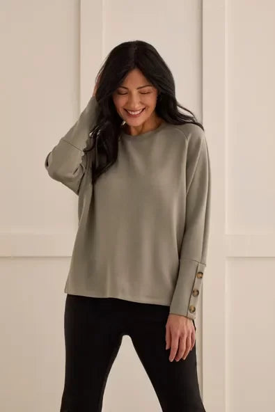 Woman wearing sage green long sleeve crew neck top with button details