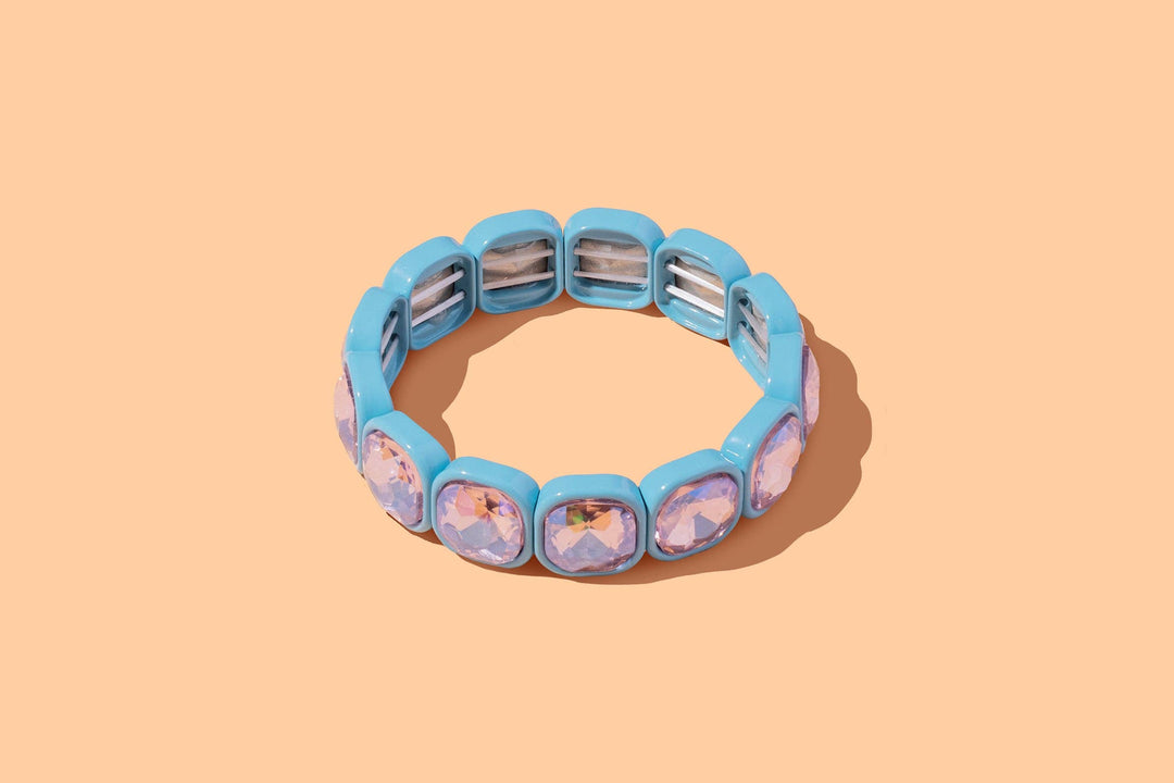 Turquoise enamel stretch bracelet with rounded iridescent purple gems on peach background