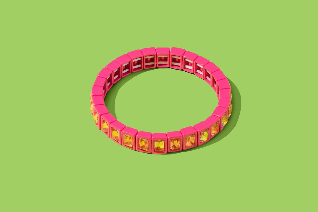 Pink enamel stretch bracelet with yellow square gems on green background