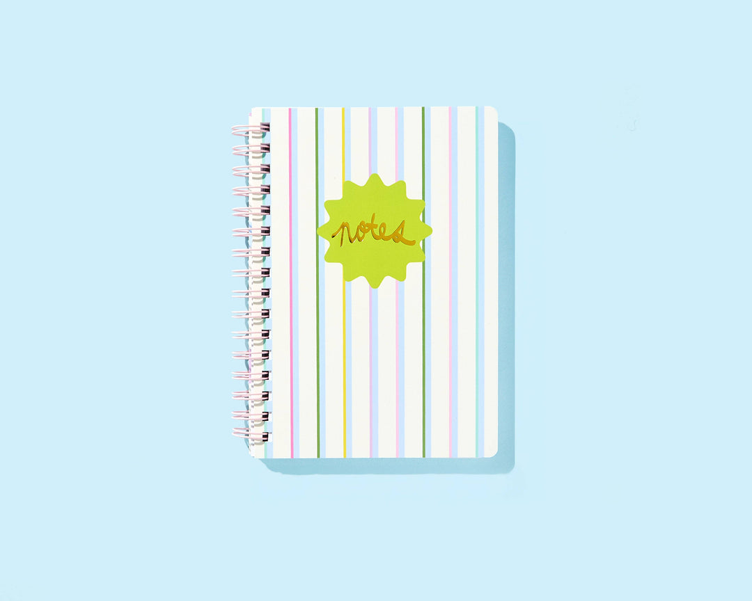 Spiral notebook with colorful vertical stripes and green notes starburst on cover