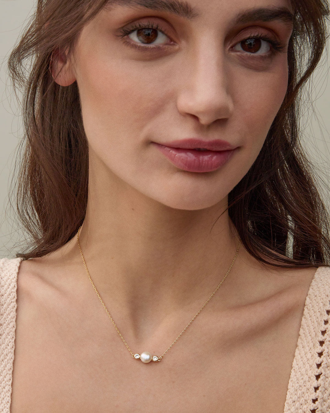 Woman wearing gold pearl necklace with white pearl and small diamonds