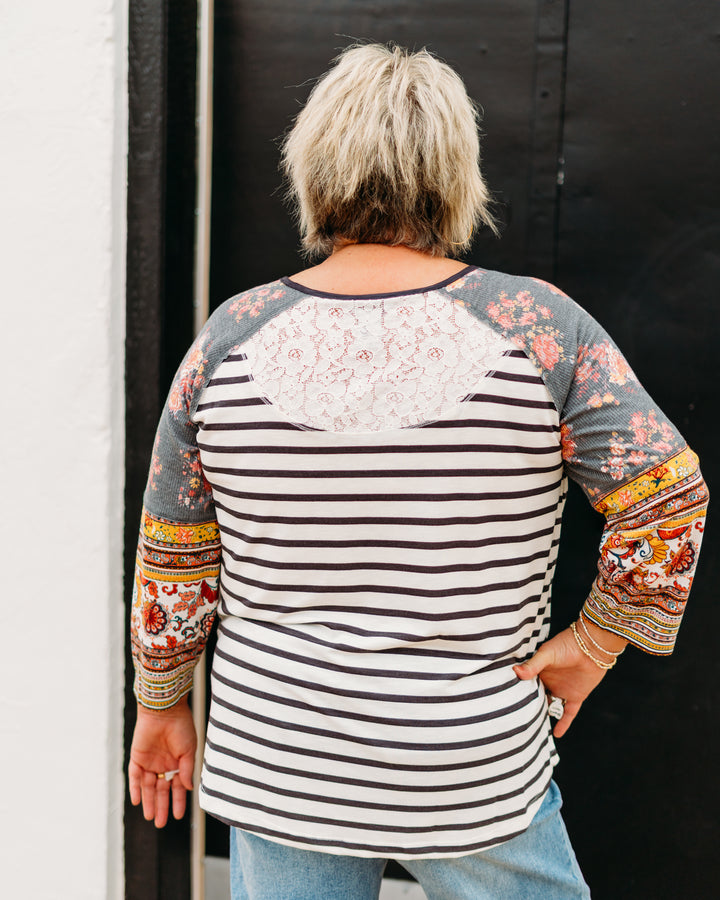 Person wearing a colorful striped shirt with patterned sleeves against a black background