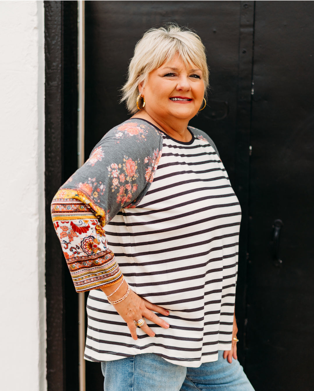 Woman wearing a striped shirt with colorful sleeves against a black background