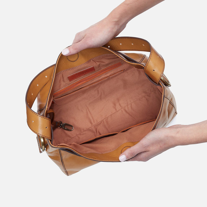 Hands holding open cognac brown leather Hobo Render handbag showing interior compartments