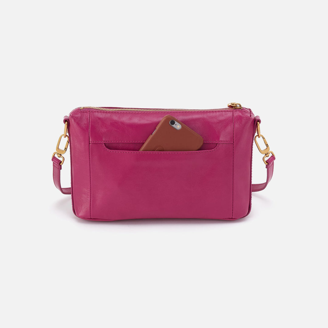 Pink leather crossbody bag with gold hardware and phone in exterior pocket