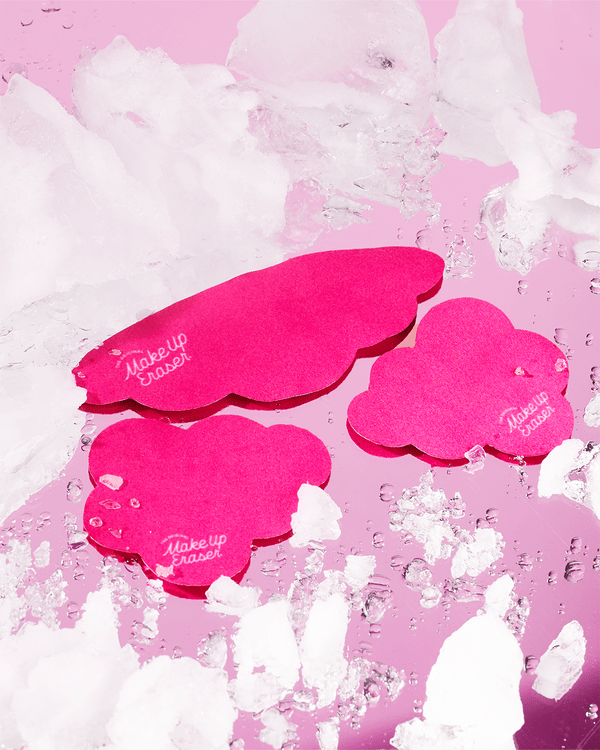 Three bright pink cloud-shaped reusable under eye patches on pink marble background