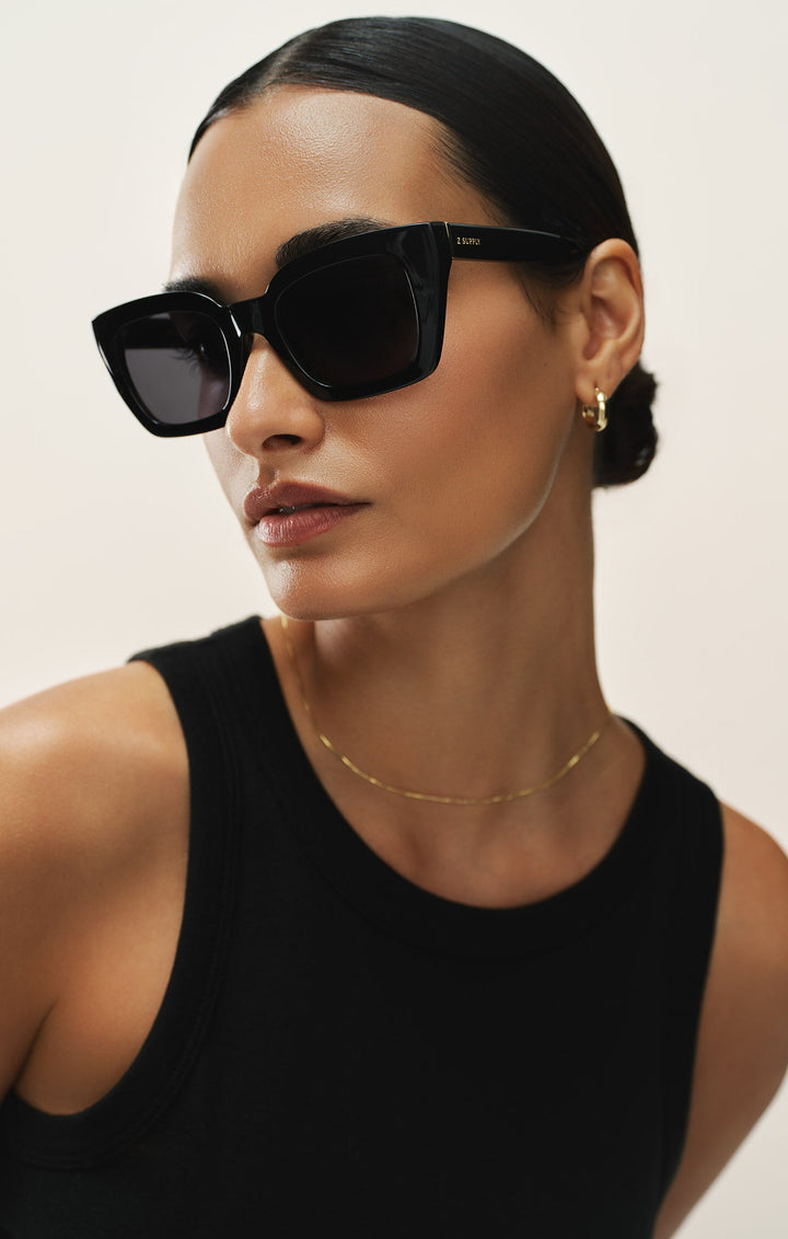 Woman wearing Z Supply Hideaway Polished Black-Grey Polarized cat-eye sunglasses with gold accessories
