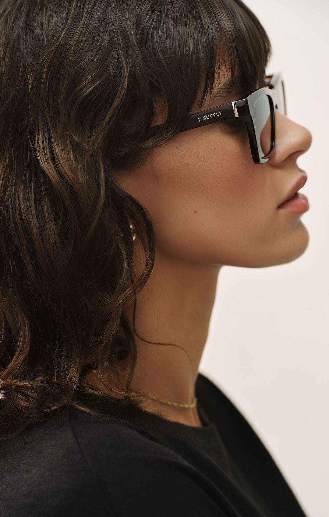 Woman wearing Z Supply Studio Polished Black sunglasses with grey polarized lenses, side profile view