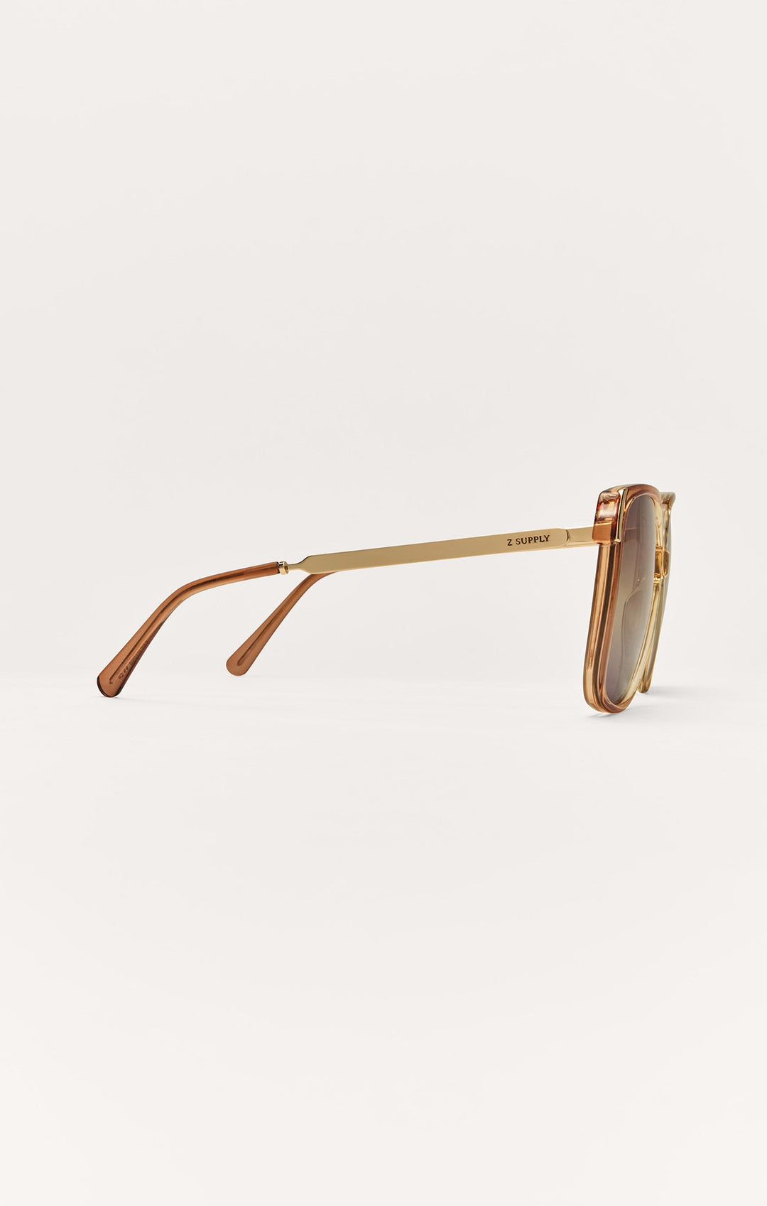 Z Supply Riviera sunglasses side view showing gold metal arms and brown transparent frames