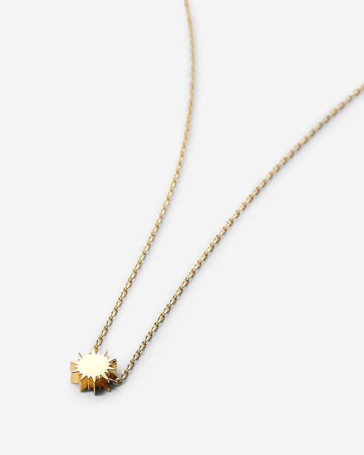 Gold sunburst pendant necklace on delicate chain against white background