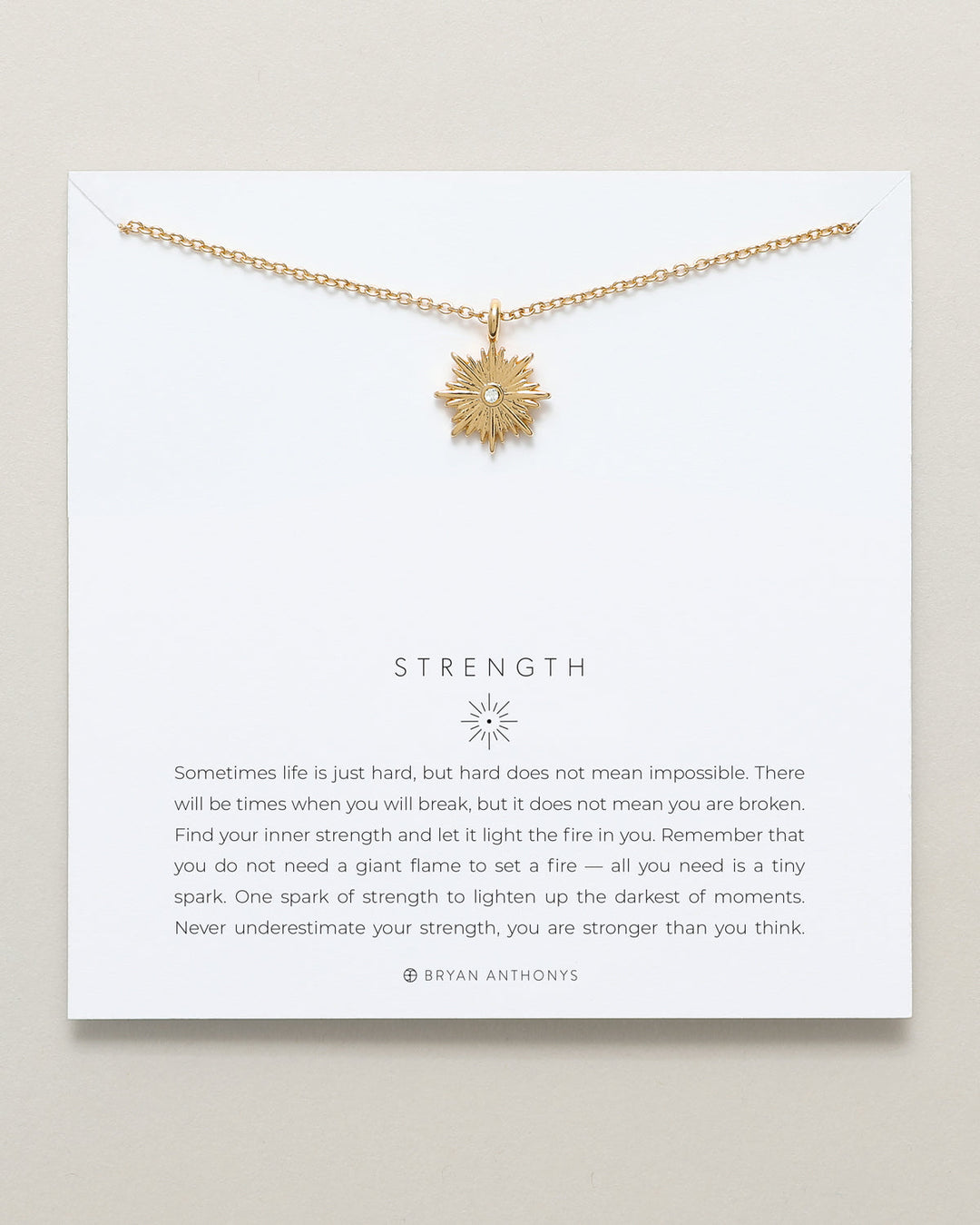 Bryan Anthonys Strength necklace with gold starburst pendant and inspirational card