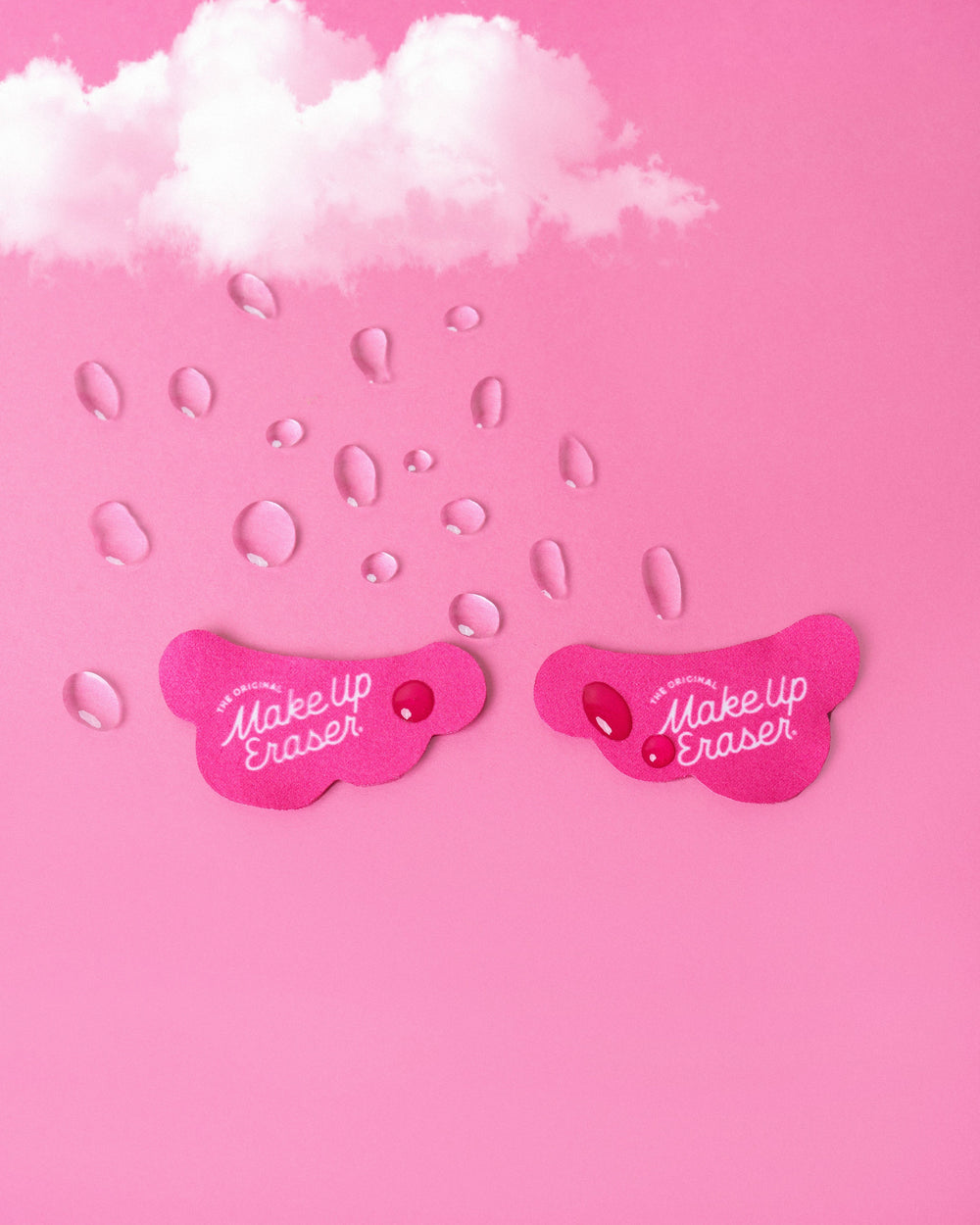 Pink cloud-shaped makeup eraser patches with water droplets on pink background