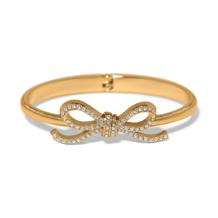 Brighton Illumina gold hinged bangle with crystal-studded bow design on white background
