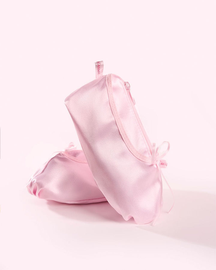 Pink ballet pointe shoes containing makeup erasers on soft pink background